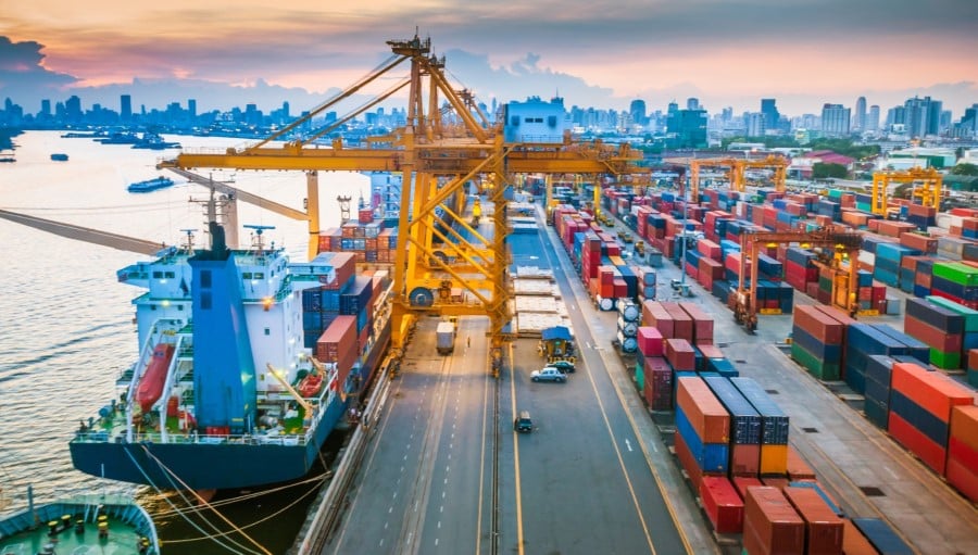 Aerial view of a port with shipping containers being loaded and unloaded from a ship.