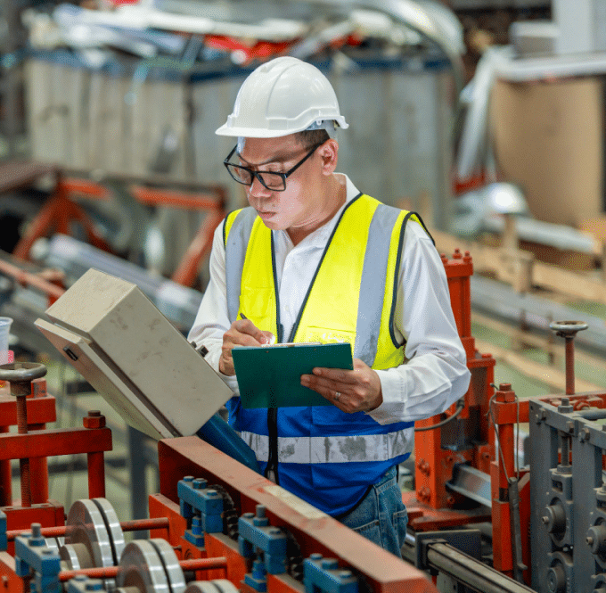 A factory worker reviewing a machine