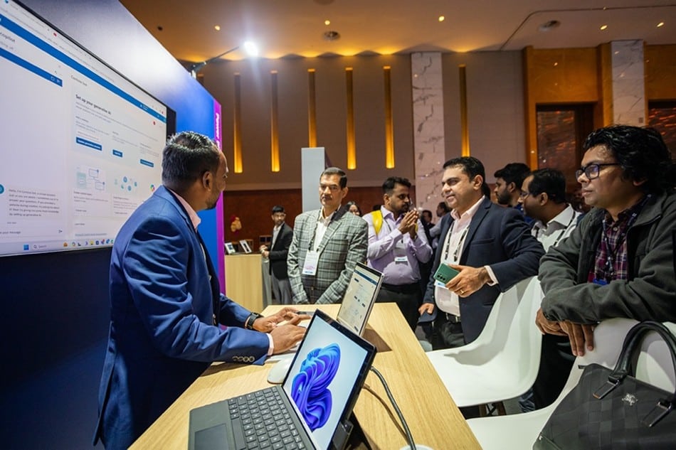 A group of men standing around a table with laptops